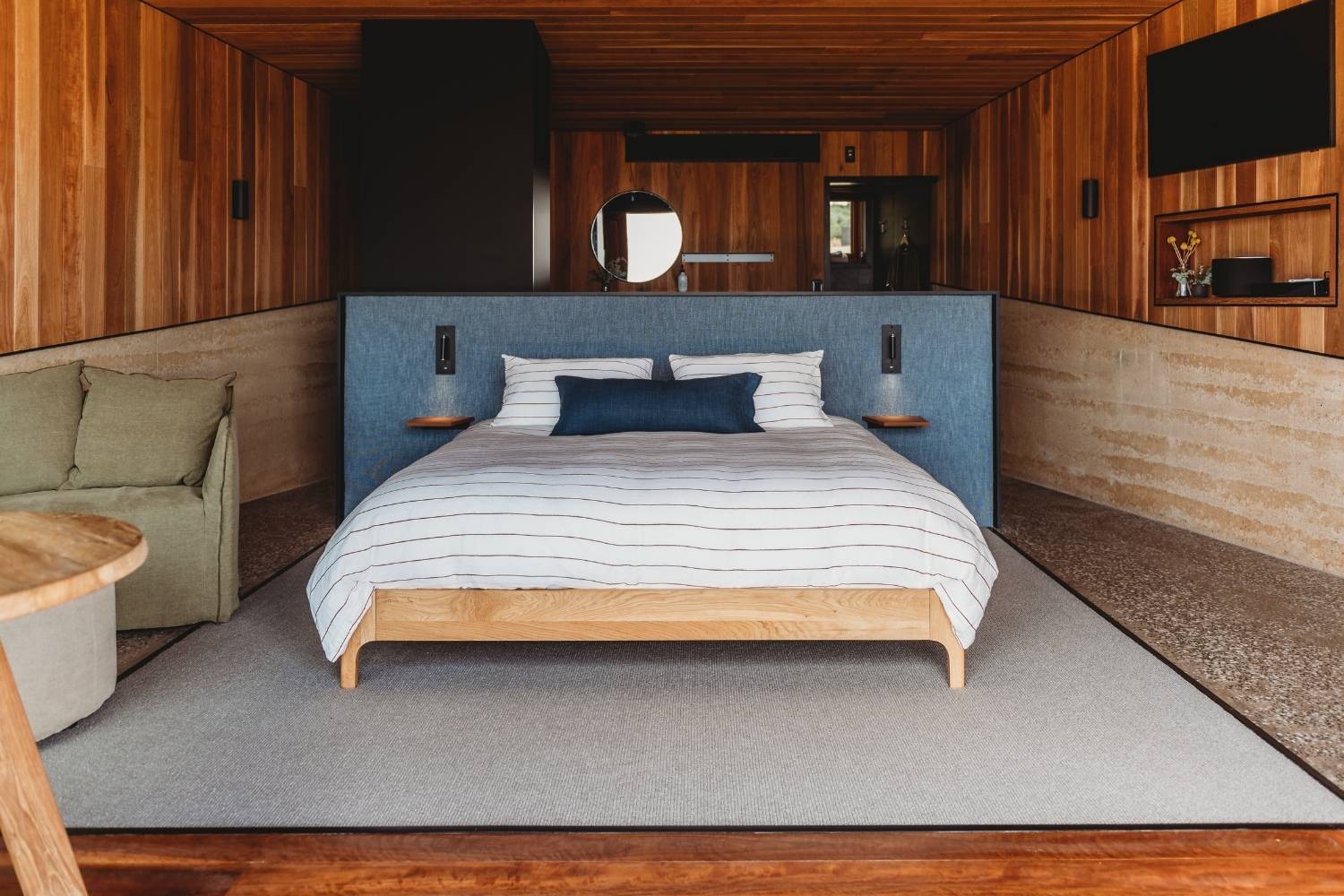 A luxurious bed adorned with a blue bed head, set against a backdrop of premium wood in a beautifully crafted bedroom space. The image exudes elegance and sophistication, with the rich tones of the wood complementing the serene blue hue of the bed head.